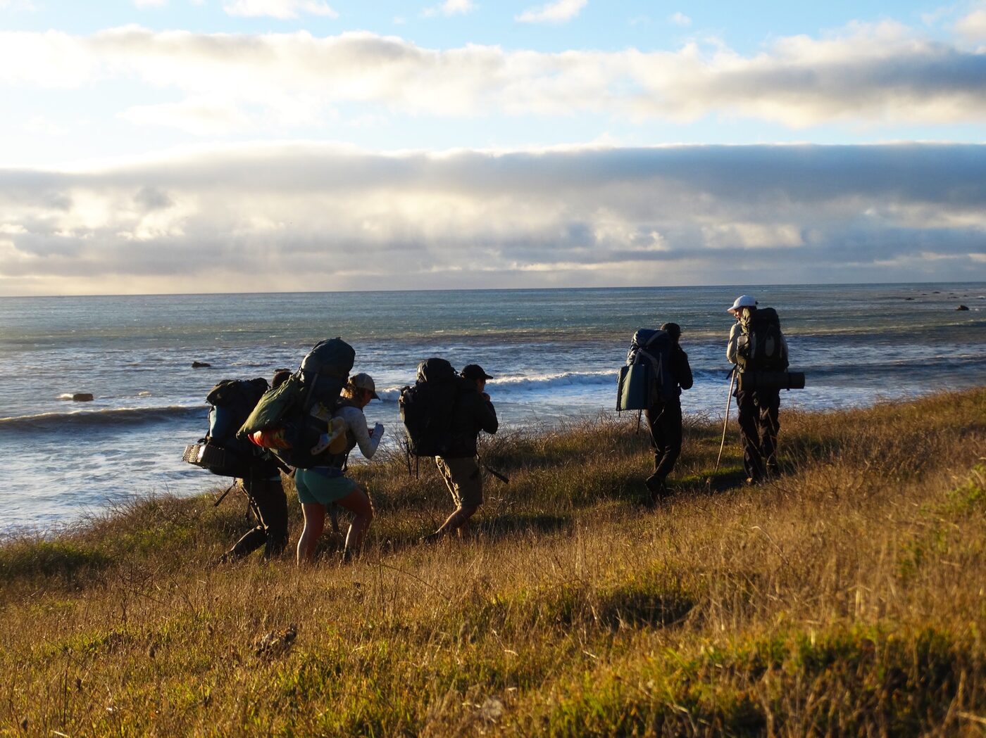 Backpackers hiking along the coast at golden hour
